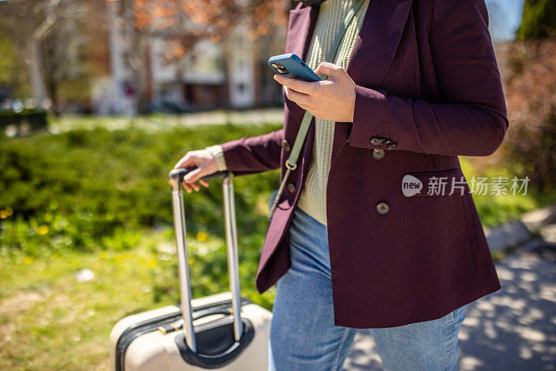 一位面目全非的年轻女子带着行李旅行，同时使用手机