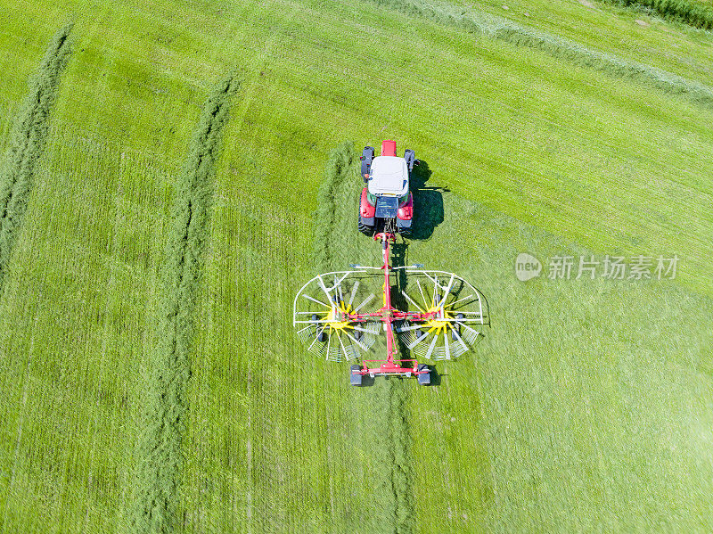 拖拉机拉着旋转耙从草地上收集干草