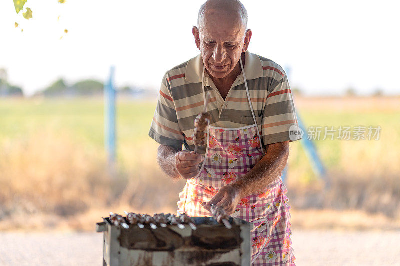 一位老人在后院为他的家人做烧烤