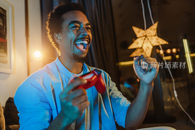 非裔美国男性电子游戏玩家兴奋地大喊着，玩着电子游戏，做着YES的手势
