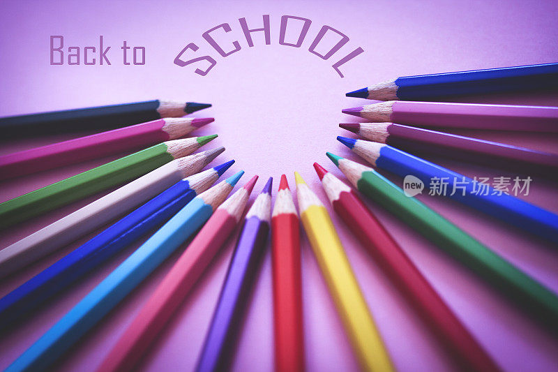 回到学校的概念，彩色铅笔在柔和的紫色背景上排列成一个圈