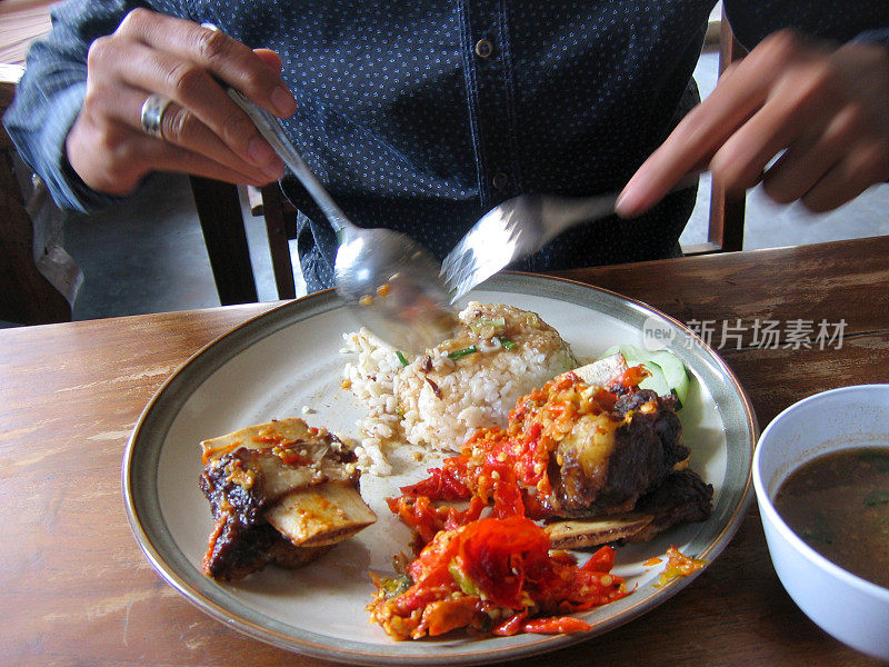 面目全非的成年男子吃着辛辣的印尼食物