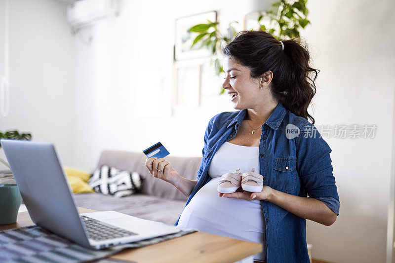 孕妇用笔记本电脑和信用卡在网上购买婴儿服装