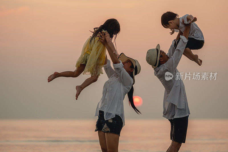 快乐的亚洲家庭在日落的海滩上玩海。全家人都喜欢带着孩子在海滩上玩耍。家庭、旅行、生活方式、度假概念。