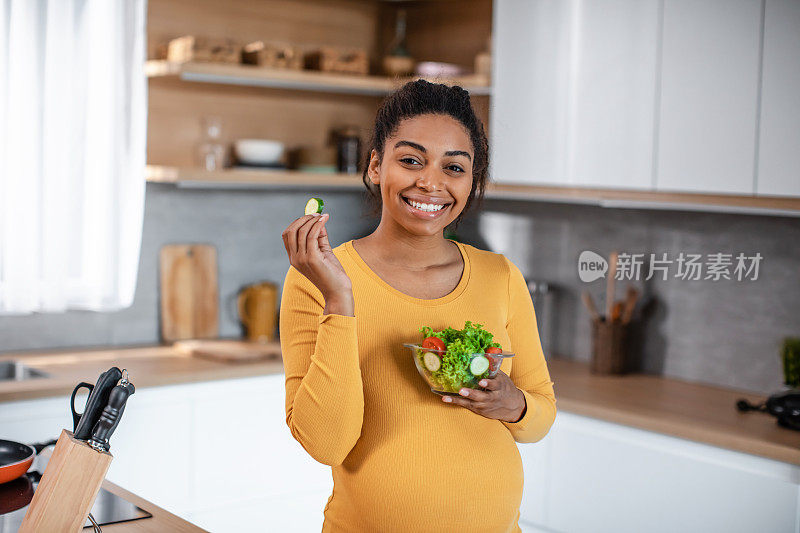很高兴饿了漂亮的千禧怀孕的非裔美国妇女的肚子吃蔬菜沙拉