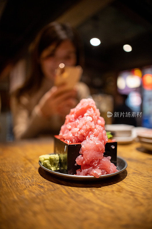 女子在居酒屋酒吧拍摄金枪鱼刺身