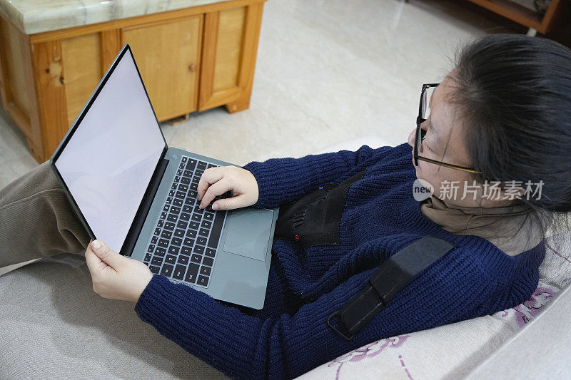 一位女士坐在沙发上使用笔记本电脑