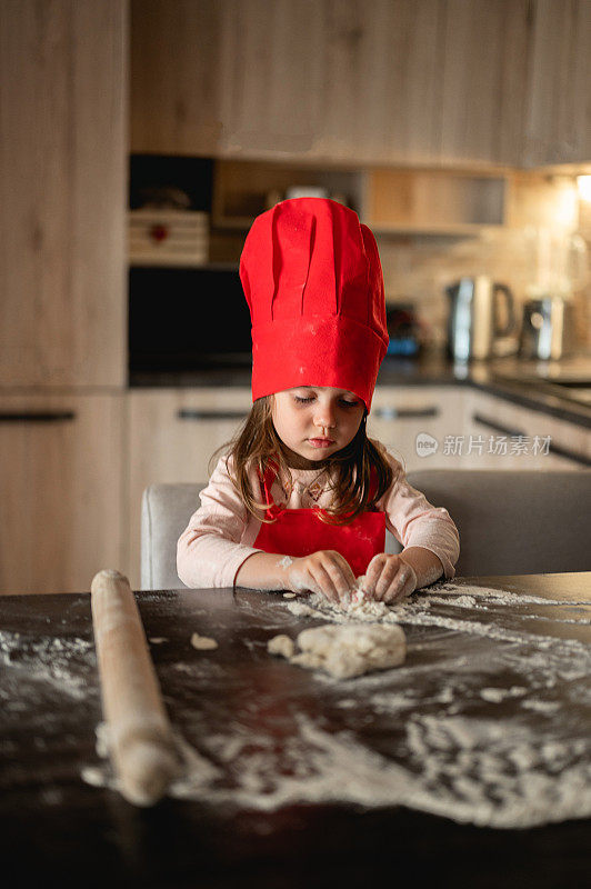 严肃的孩子在厨房里像厨师一样玩面粉。