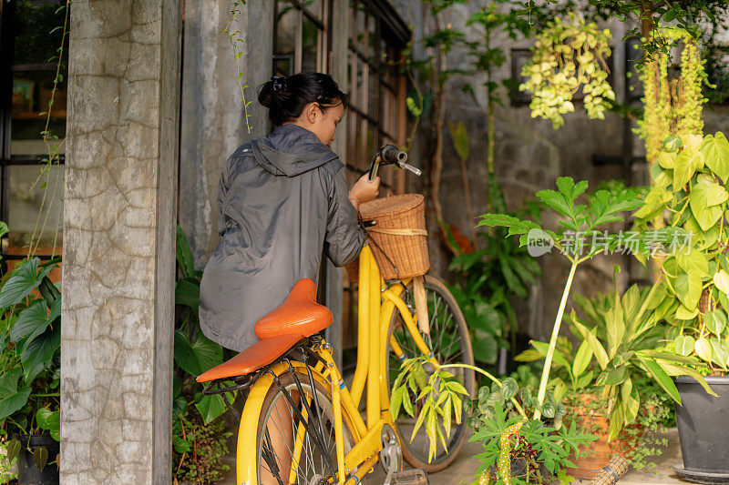 一个亚洲女孩把黄色自行车与藤篮子在一个有趣的骑自行车绕村