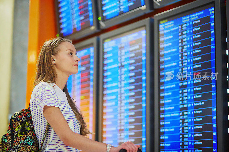 一位年轻女子在机场看航班信息板
