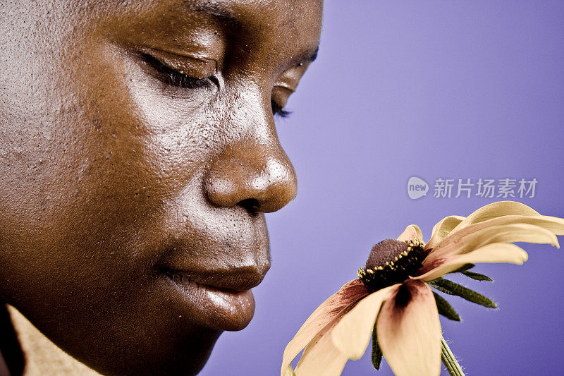 非洲女人闻着花香，闭着眼睛