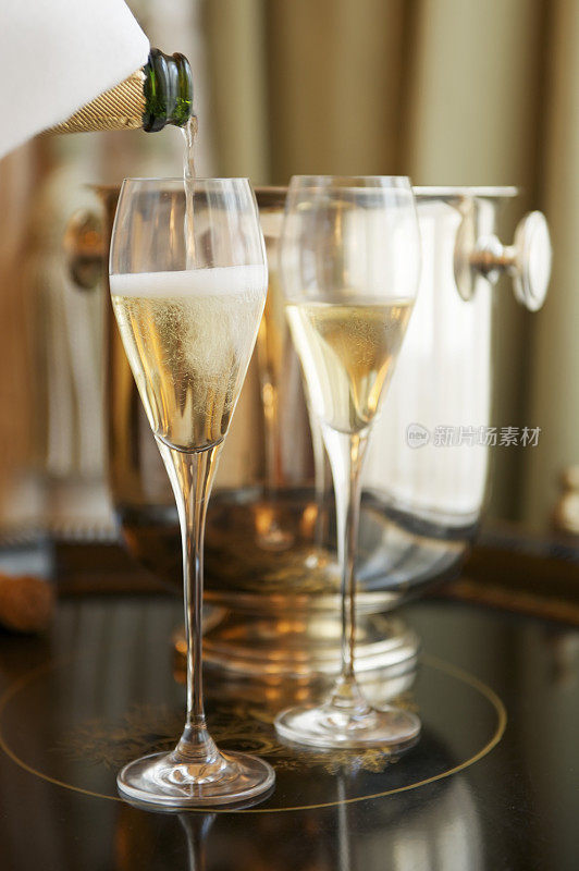 用餐巾把香槟倒进两个玻璃杯里