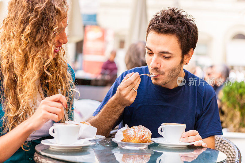 一对夫妇用卡布奇诺和奶油蛋糕吃早餐