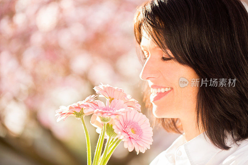 成熟的女人闻着非洲菊花束