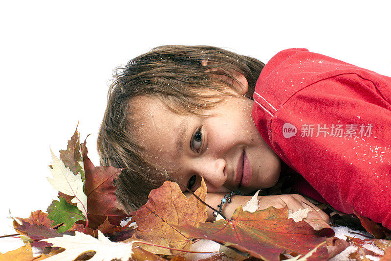 微笑的男孩在秋天的树叶。