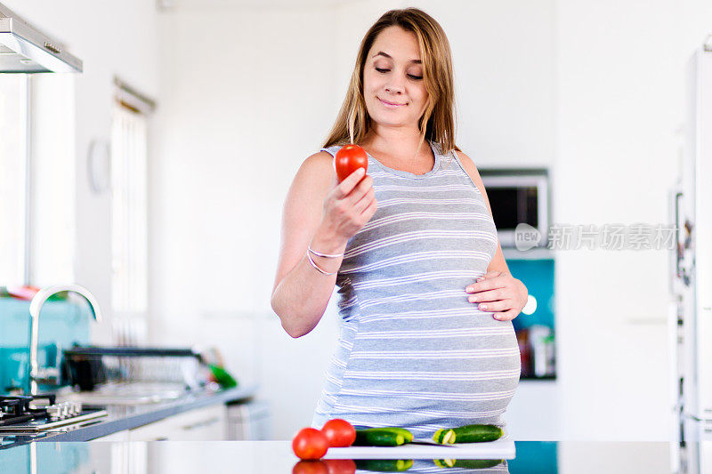 微笑的孕妇在厨房准备健康的食物