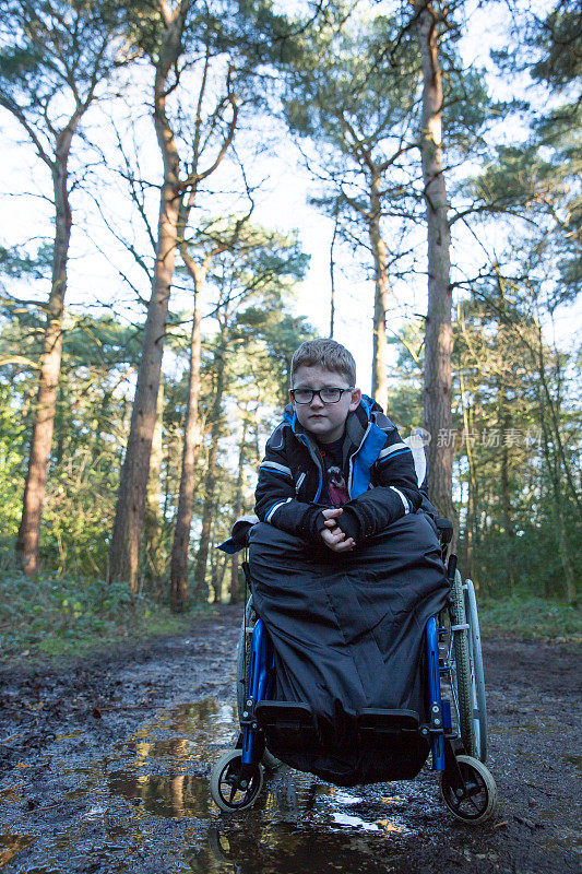 男孩残疾在轮椅上湿泥森林轨道