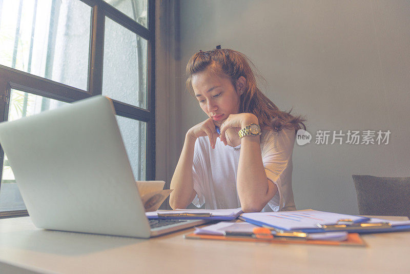 女人在笔记本电脑旁专心阅读文件