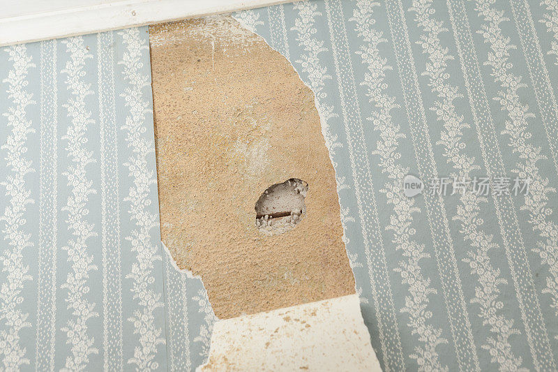 墙纸破损的旧房子墙上的石棉检查洞