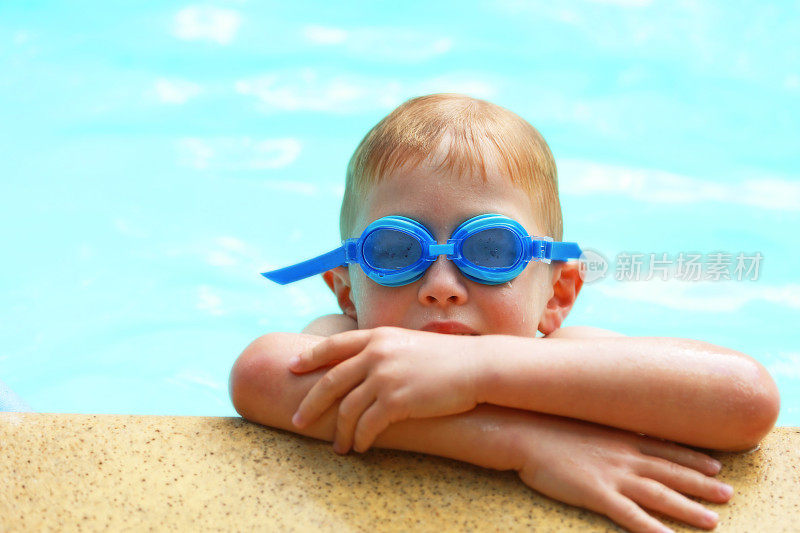 在室外游泳池戴着蓝色泳镜的孩子