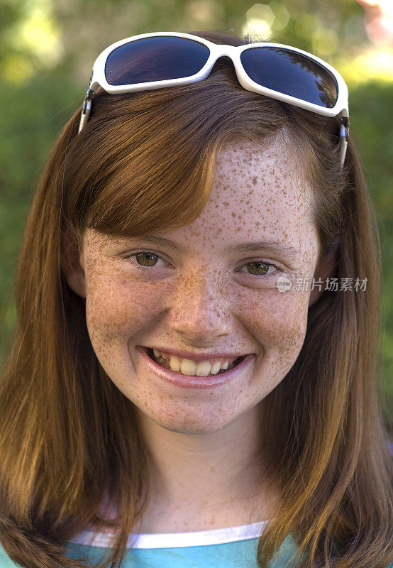 雀斑脸红发儿童，前青春期女孩戴着太阳镜微笑