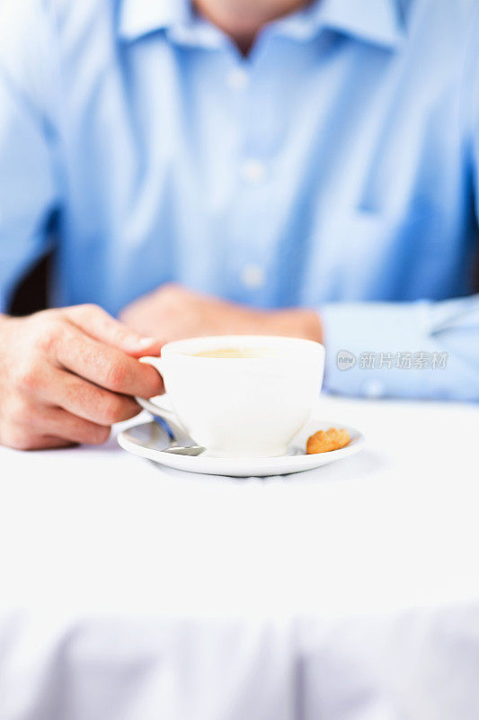 餐厅里拿着咖啡杯和咖啡碟的男人的腹部