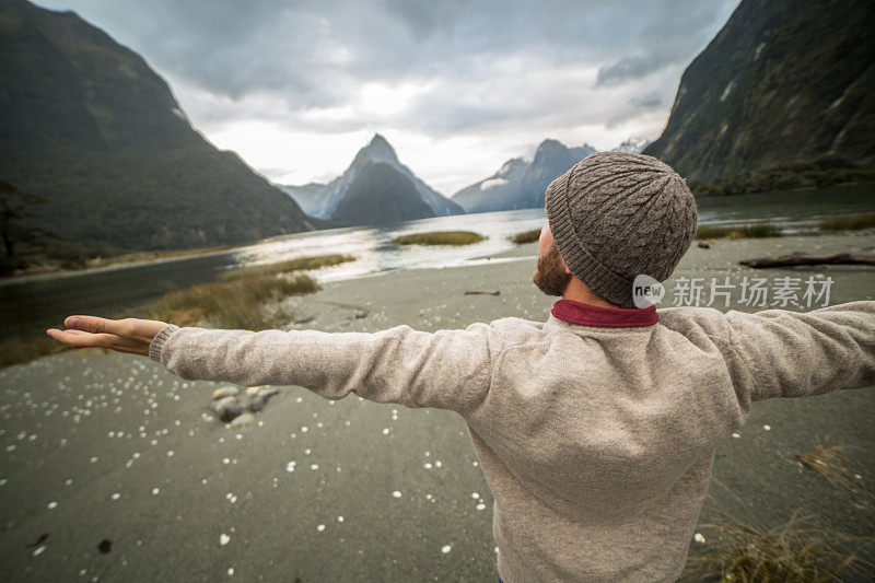 年轻人在大自然中伸开双臂，山的背景