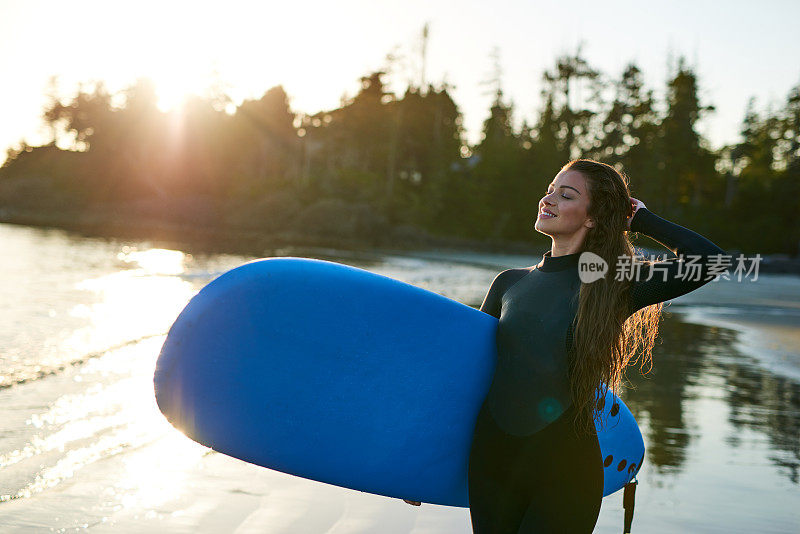 强壮美丽的年轻女人在海滩上冲浪