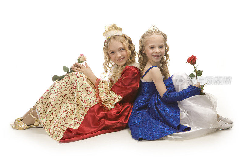 两个美丽快乐的小公主坐在地板上，拿着玫瑰花。