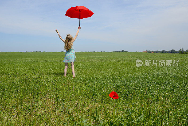 打着红阳伞的少女站在绿色草地上