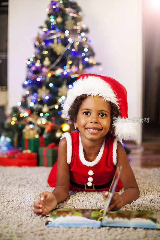 一个非裔美国小女孩在圣诞树前读书