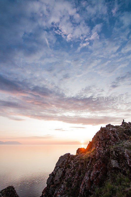 清晨的夕阳环绕着橙色和玫瑰色的岩石和奥尔孔岛和贝加尔湖的山脉