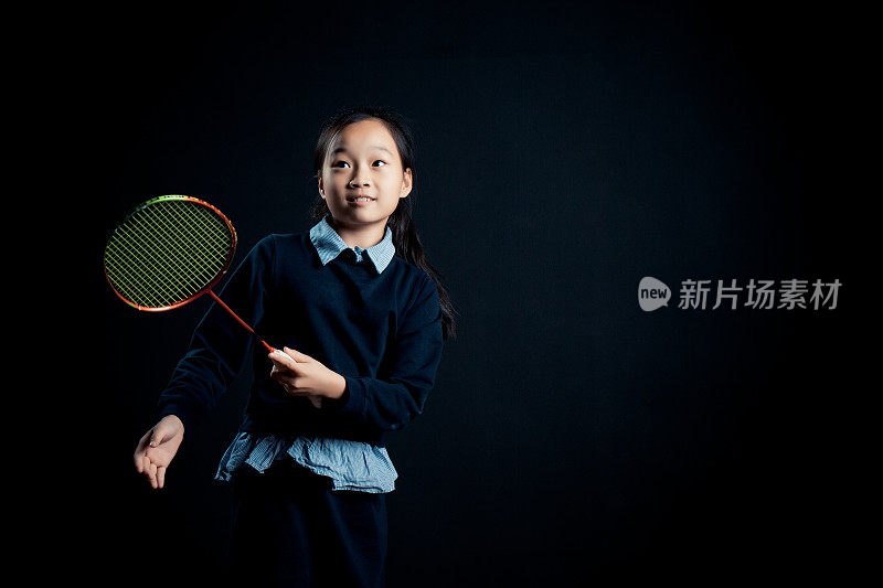 小女孩打羽毛球-孤立在黑色背景
