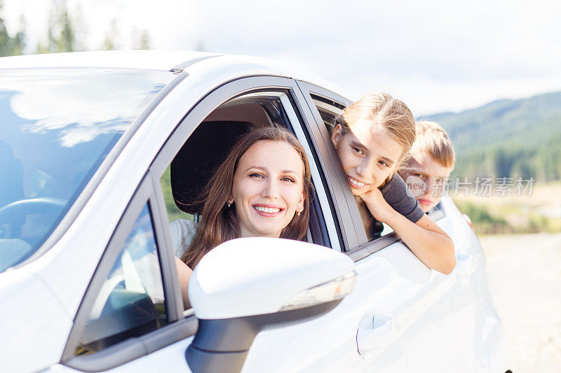 快乐的年轻妈妈和她的孩子们坐在车里
