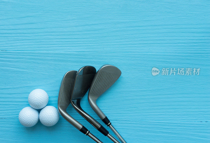 高尔夫球杆，高尔夫球放在蓝色的木桌上
