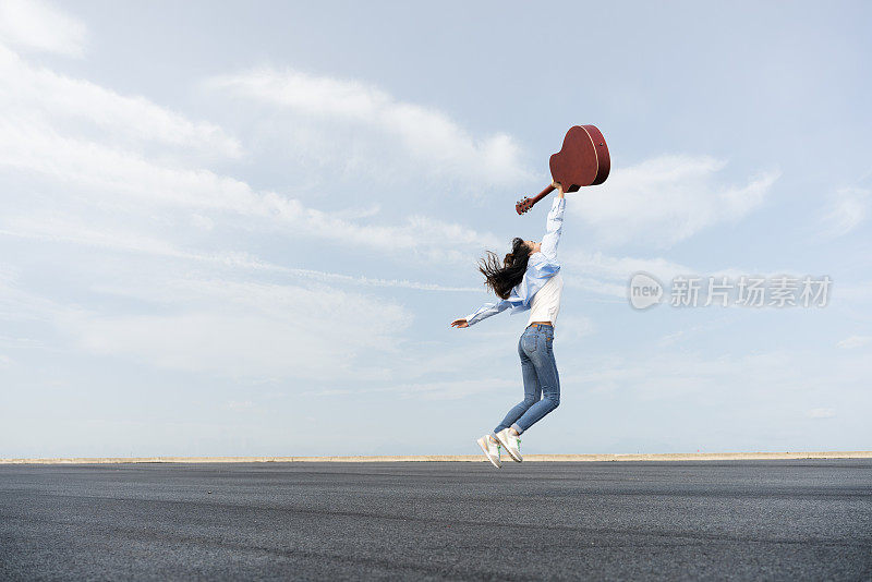 美丽的女人把吉他举向天空