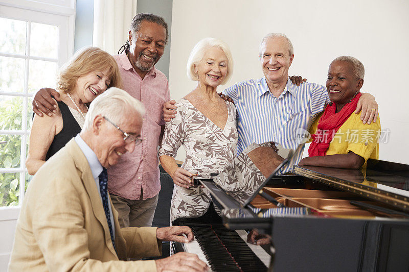 一群老年人站在钢琴旁一起唱歌