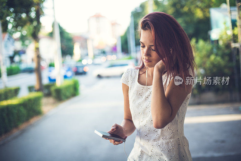 优雅的年轻女子在城里听她的音乐