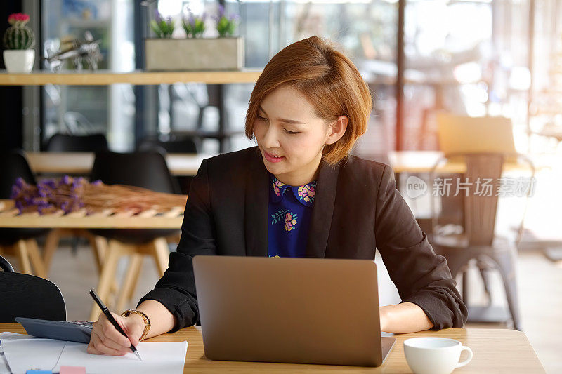 一个年轻的亚洲女商人在咖啡馆做笔记的剪影。