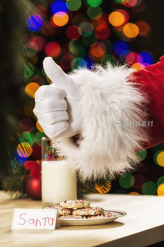 圣诞老人为一个孩子在平安夜留下的饼干和牛奶竖起大拇指