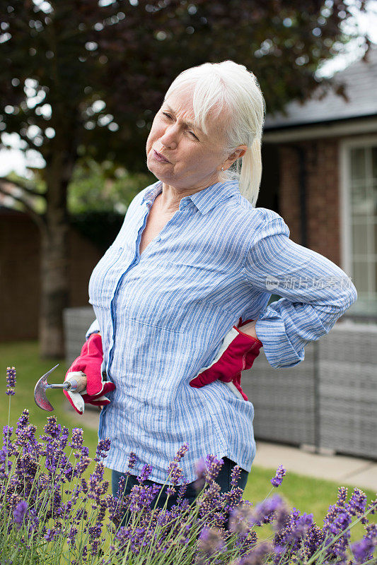 老年妇女在家里园艺时背痛