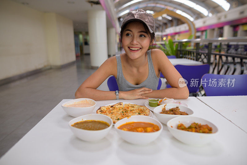 年轻美丽的亚洲女游客在餐厅享受印度美食的肖像