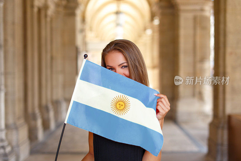 快乐的年轻女子用阿根廷国旗遮住脸