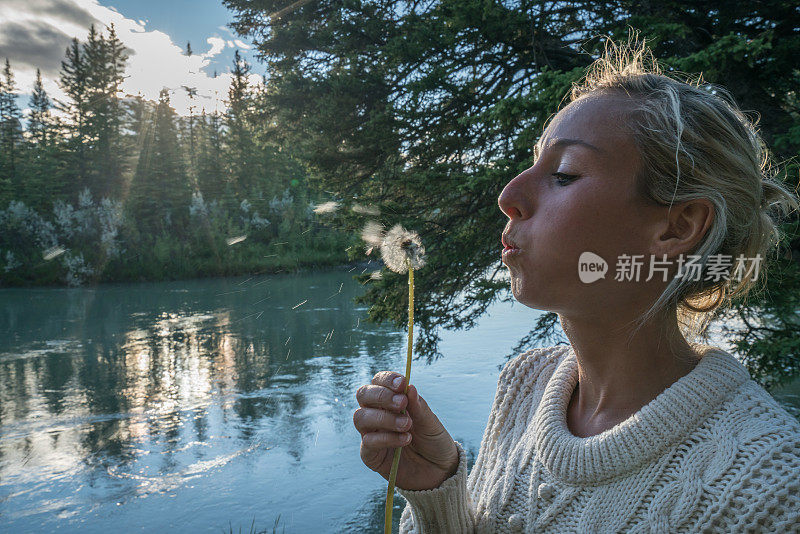 一位年轻的女子正在向空中播撒蒲公英的种子