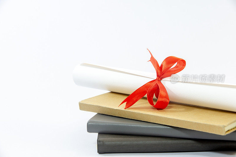 恭喜你毕业。学士帽和毕业卷，用红丝带系着，放在一堆破旧的书上，还有复印的空间