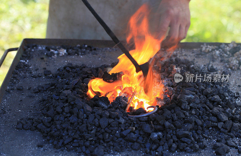 铁匠在灼热的煤火上加热熨斗