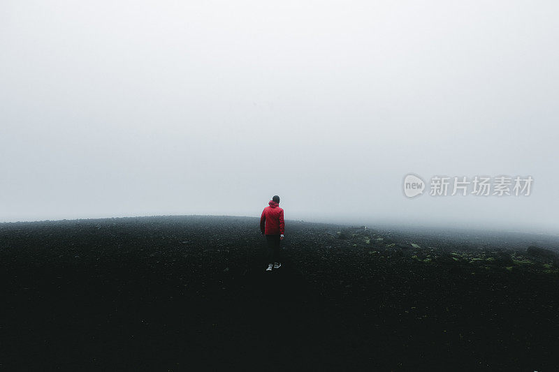 穿着红色夹克的人徒步穿越冰岛的火山景观和风