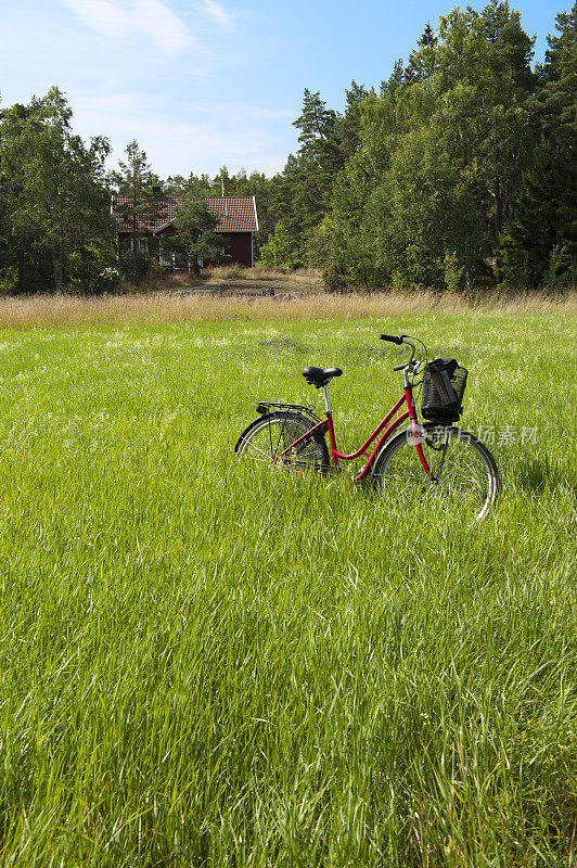 在草地上骑自行车，后面是农舍