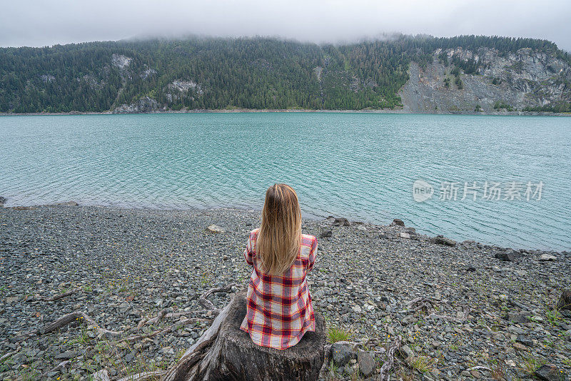 阴天，年轻女子在湖边凝望大自然