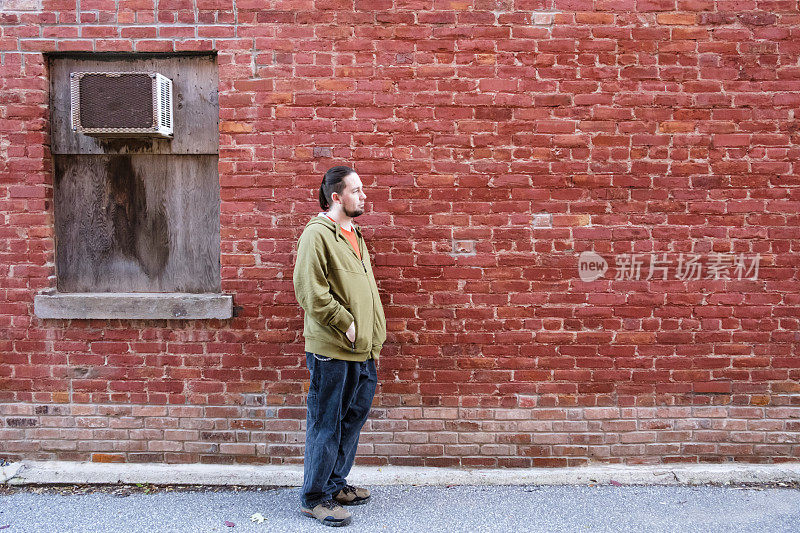 一名男子站在一堵有复印空间的旧砖墙前